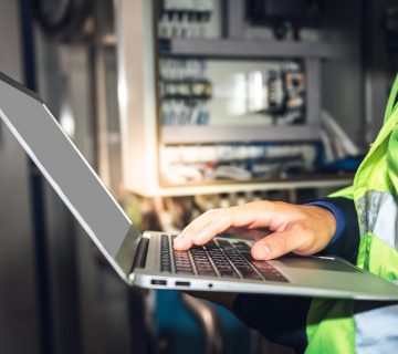 Engineer man using computer notebook for Checking the electrical system Of the machine in the industrial factory, to engineering and industry concept.